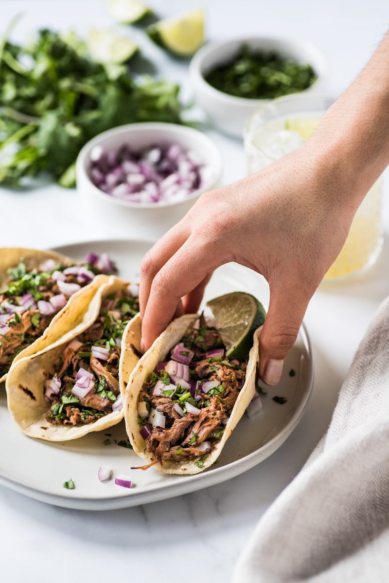 A hand grabbing a barbacoa taco