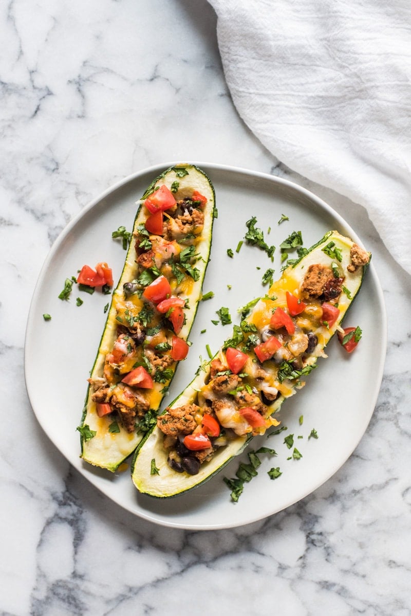 Ground Turkey Zucchini Boats topped with tomatoes and chopped cilantro.
