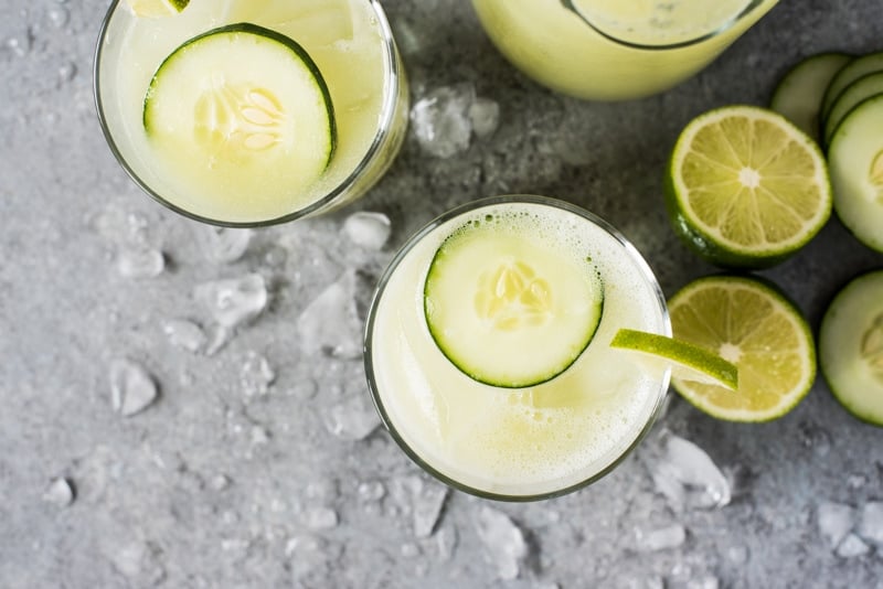 Cucumber Agua Fresca water in a glass filled with ice and topped with a slice of fresh cucumber.