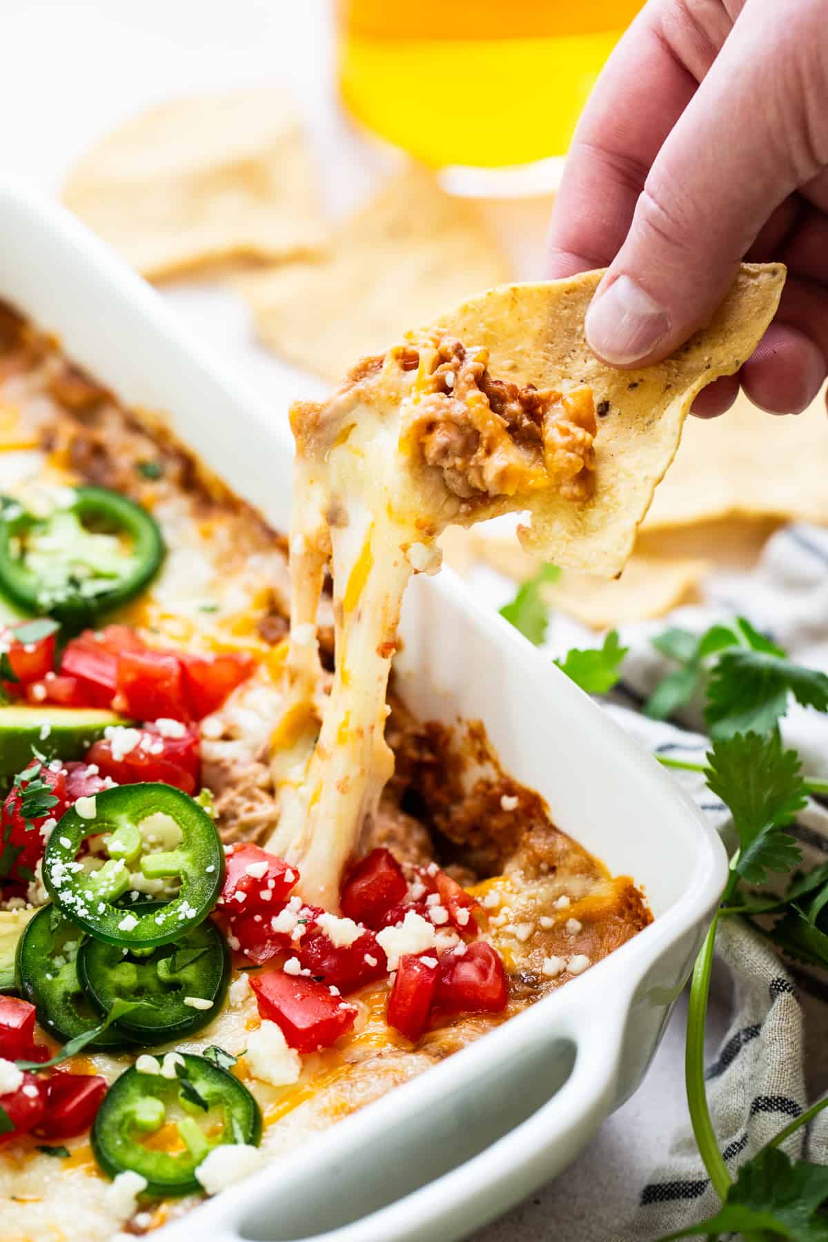 A tortilla chip pulling melted cheese and bean dip.