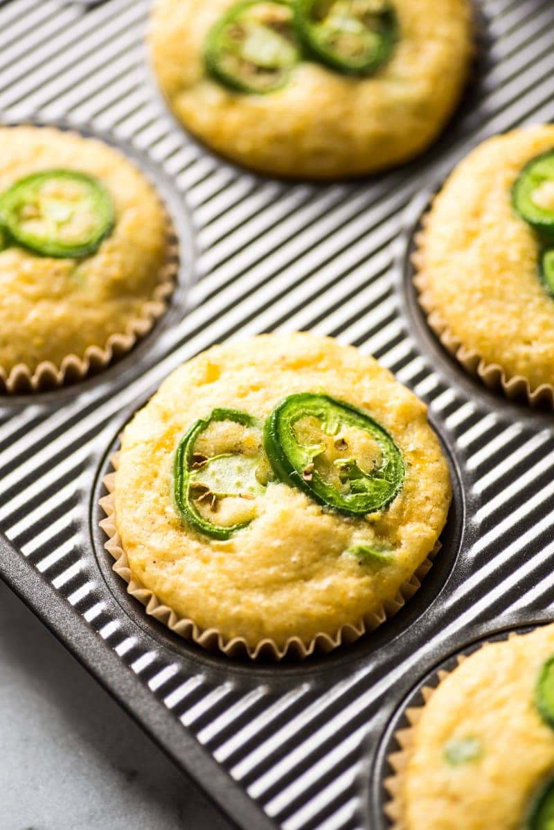 Jalapeno Cornbread muffins topped with sliced jalapenos in a muffin tin.