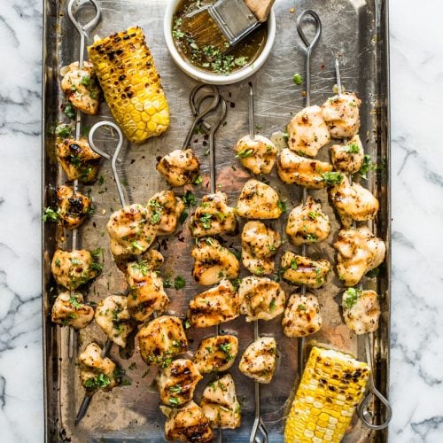 Grilled chicken kabobs on a baking sheet.