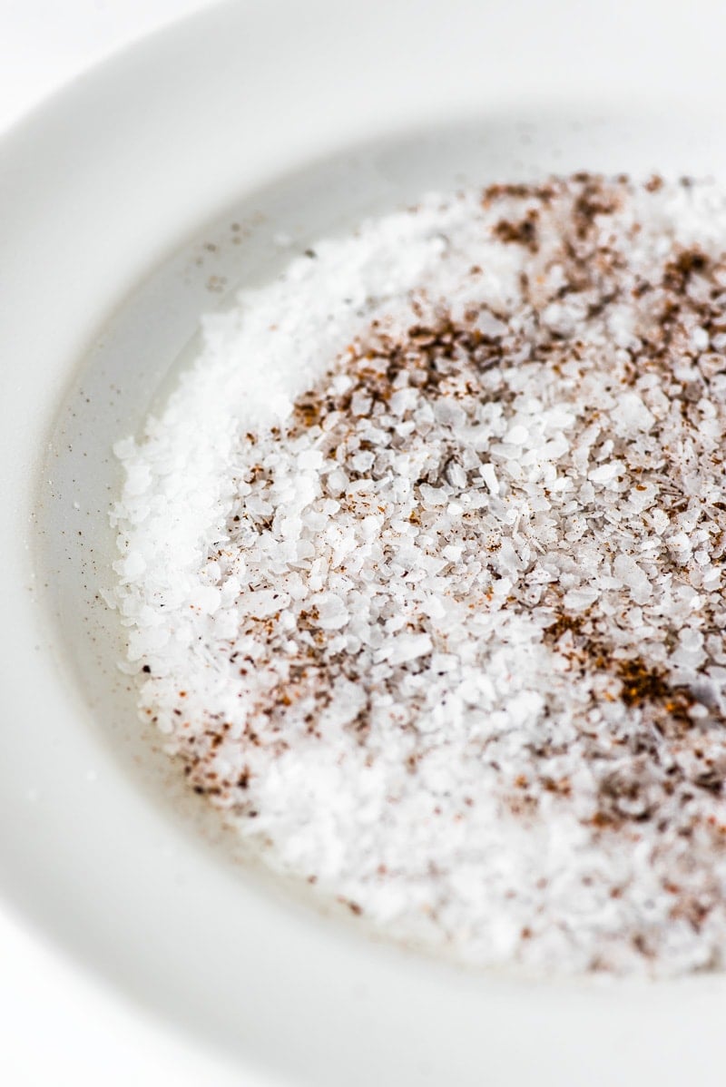Coarse sea salt and chili powder on a white plate for the rim of a michelada.