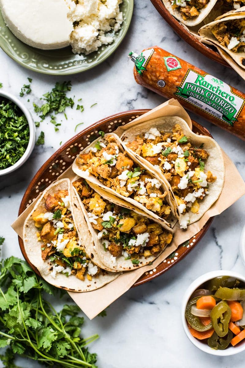 Breakfast tacos filed with eggs, chorizo and potatoes on a brown Mexican-style plate.