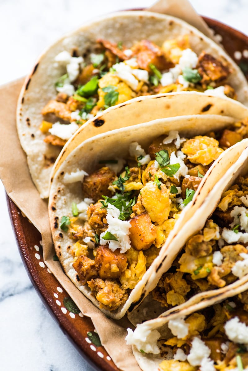 Close up photograph of breakfast taco filling made with eggs, potatoes and chorizo topped with cilantro and queso fresco.