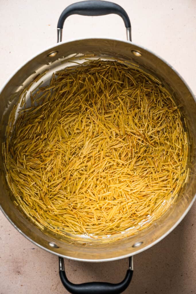 Fideo noodles being toasted in a pot for sopa de fideo