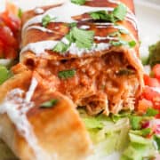 A chimichanga filled with shredded chicken, refried beans, salsa, and cheese sliced in half to see the inside.