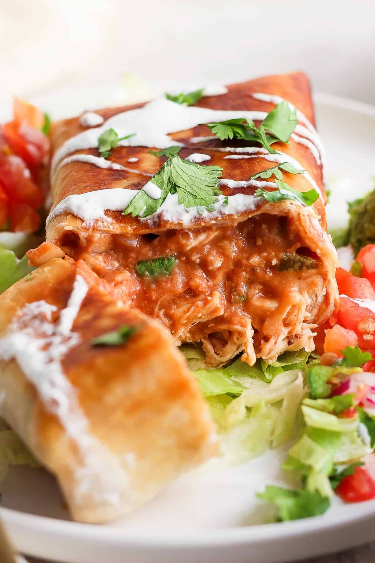 A chimichanga filled with shredded chicken, refried beans, salsa, and cheese sliced in half to see the inside.