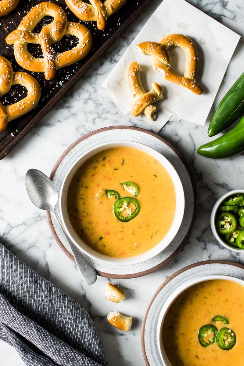 Beer cheese soup on a table with pretzels.