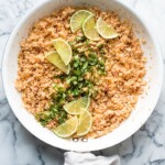 Mexican cauliflower rice in skillet garnished with cilantro and lime.