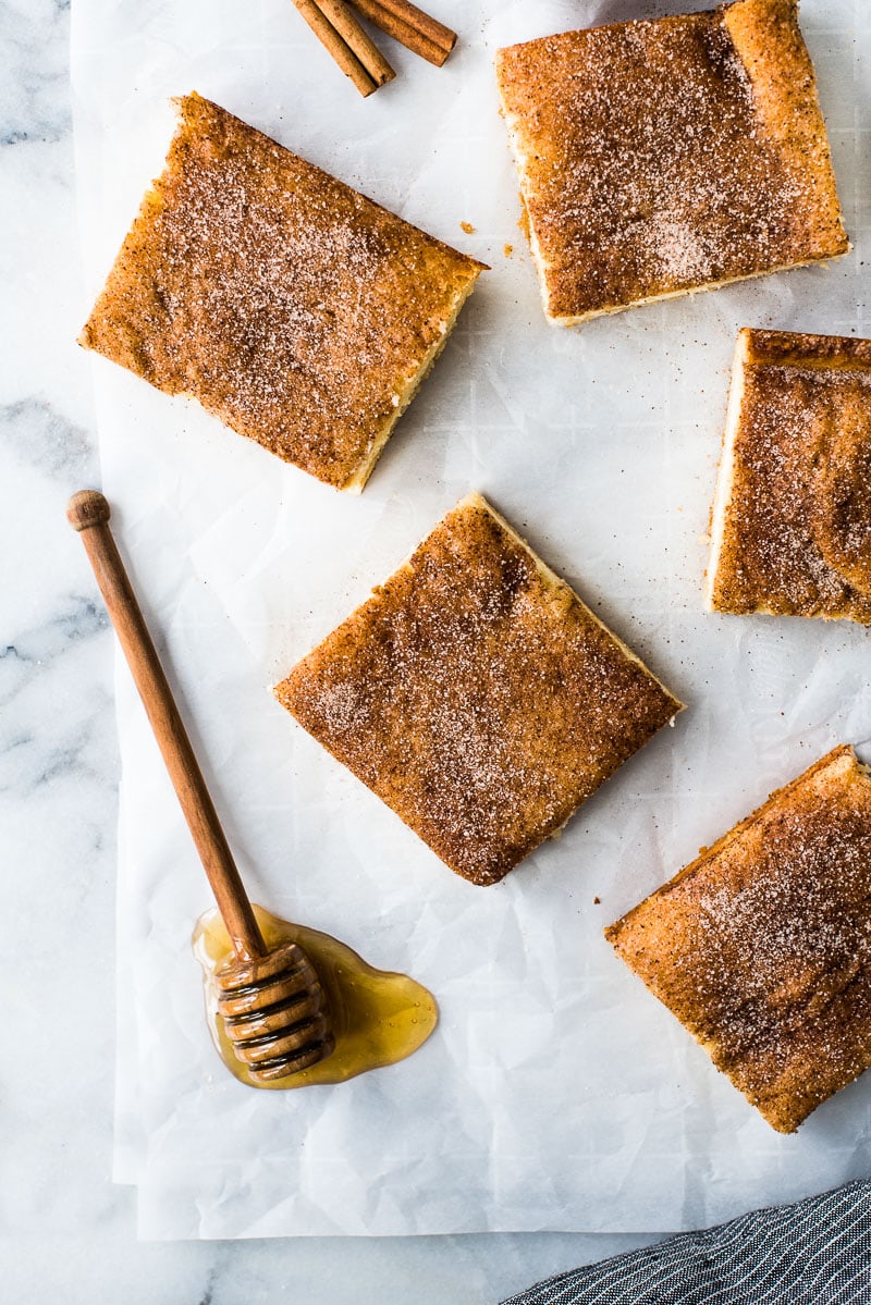 Slices of sopapilla cheesecake covered with cinnamon sugar on a table.