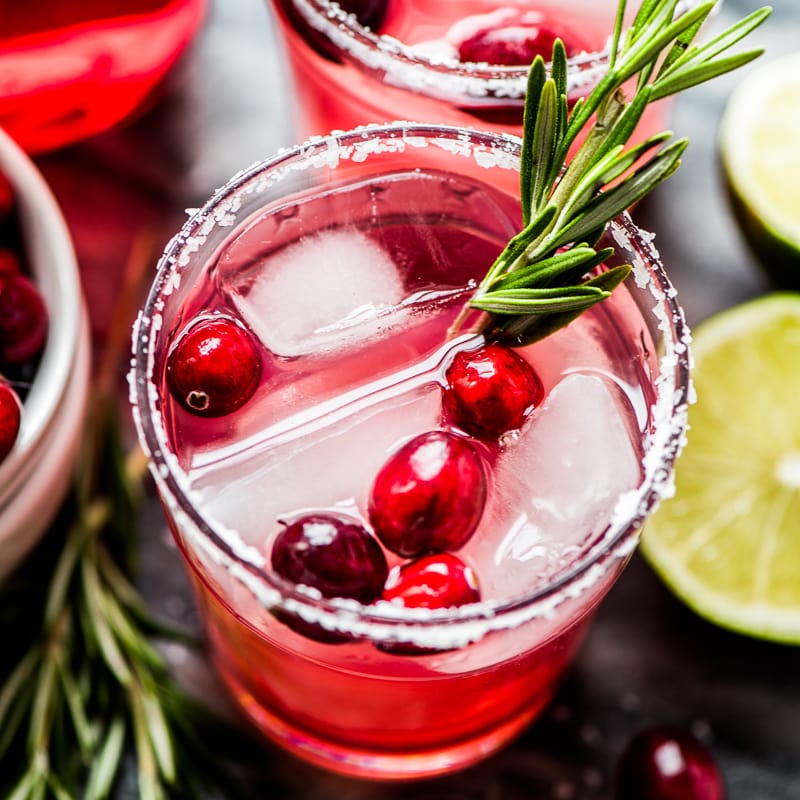 Cranberry Margarita in a glass garnished with fresh cranberries and a fresh rosemary sprig.