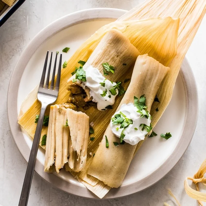 Chicken Tamales on a plate sitting on corn husks.