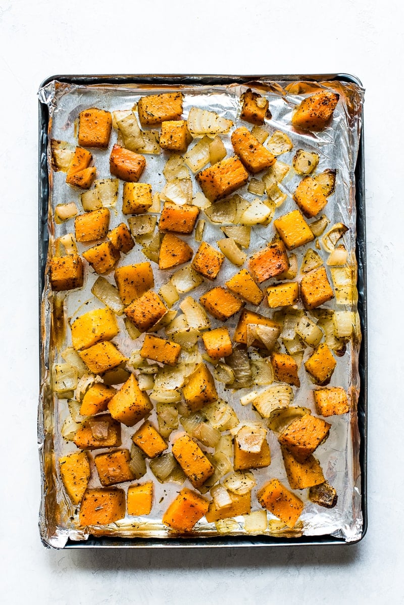 Roasted butternut squash and onions on a large baking sheet