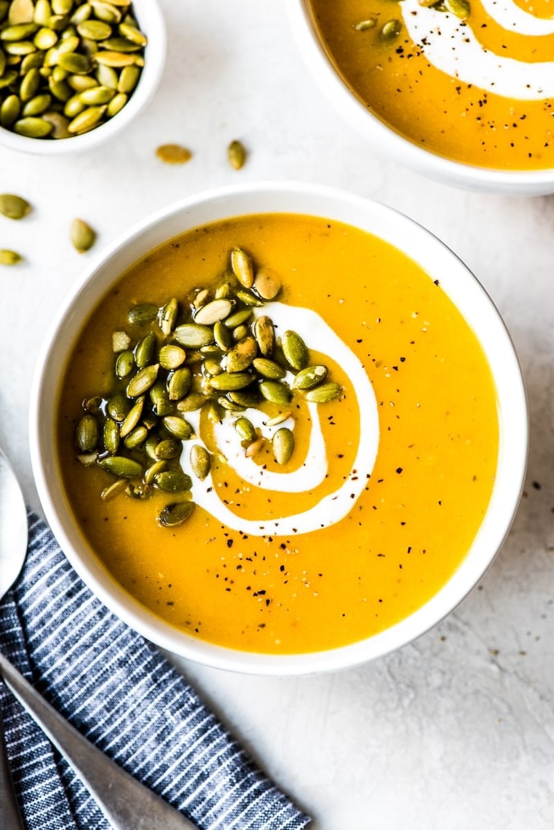 Roasted butternut squash soup in a white bowl topped with pepitas.