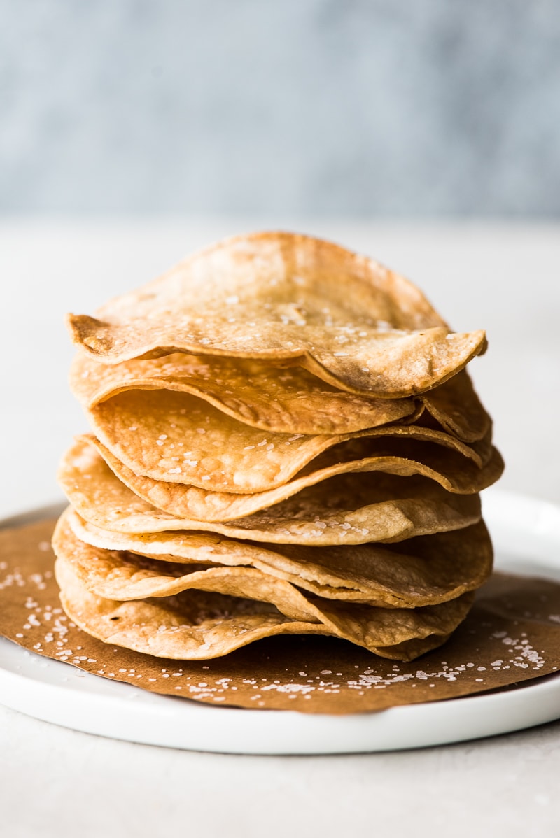 Homemade tostada shells on a white plate.