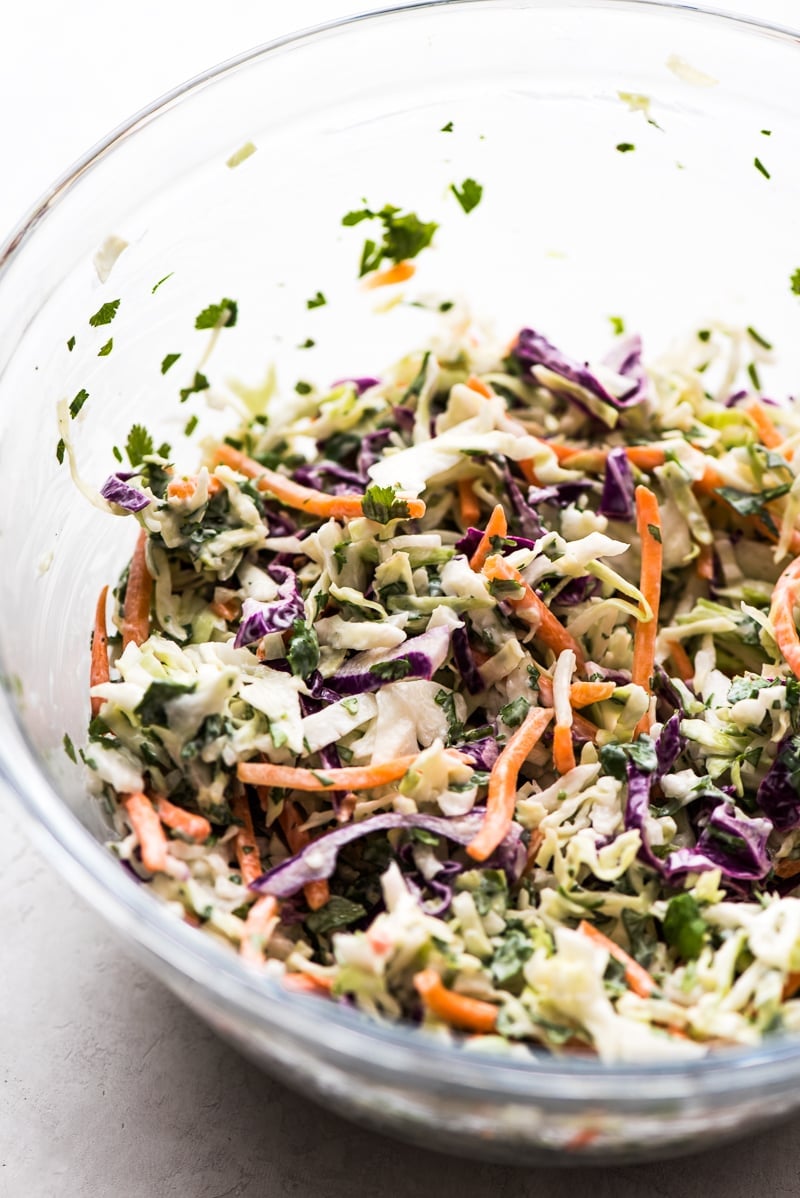 A creamy cabbage slaw made with green and red cabbage, carrots and cilantro covered in mayo and lime juice for a Baja Fish Tacos recipe.