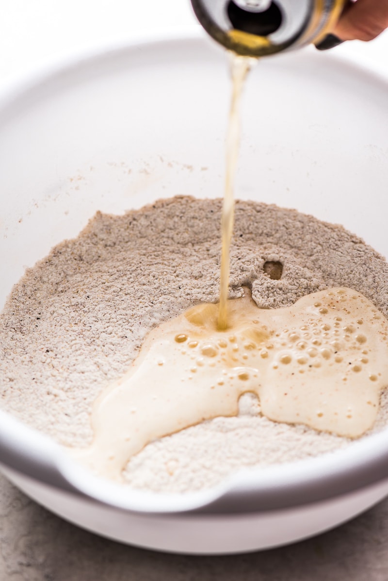 Beer being poured into a flour mixture for a Baja Fish Tacos recipe.