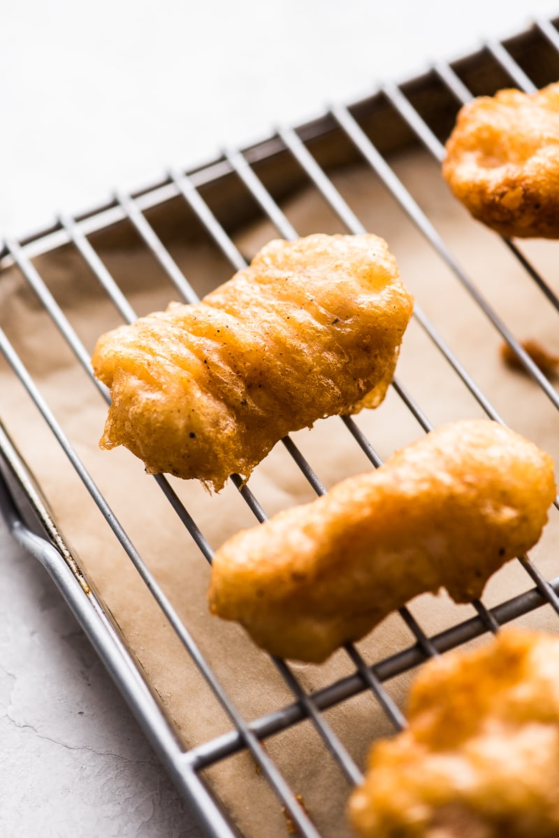 Fried fish on a sheet pan draining off excess oil.