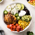 Chicken burrito bowl made with chicken, black beans, cilantro lime rice, corn, tomatoes, guacamole and sour cream.