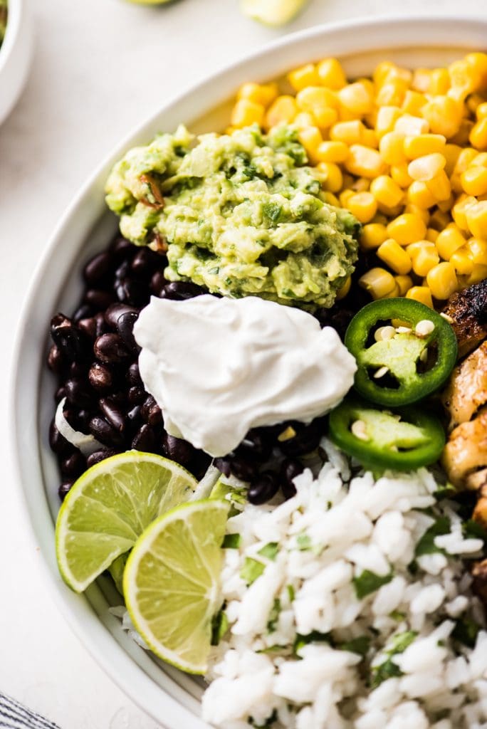 A chicken burrito bowl made with cilantro lime rice, black beans, corn, guacamole and plain Greek yogurt.