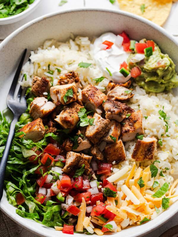 Chicken Burrito Bowls with shredded lettuce, pico de gallo, cheese, and guacamole.