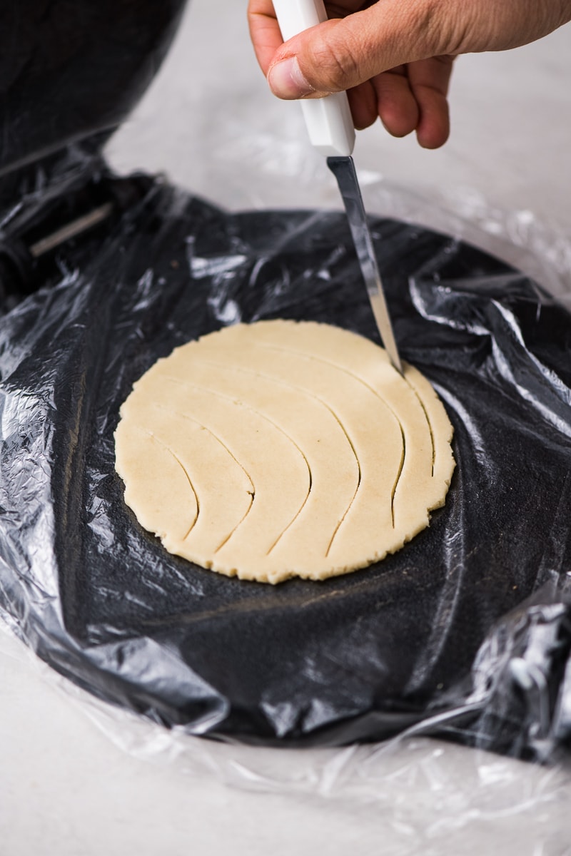 Concha bread topping being carved with a small pairing knife.