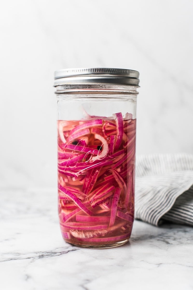 Beautiful pickled onions in a glass jar that are ready to eat in only 30 minutes.