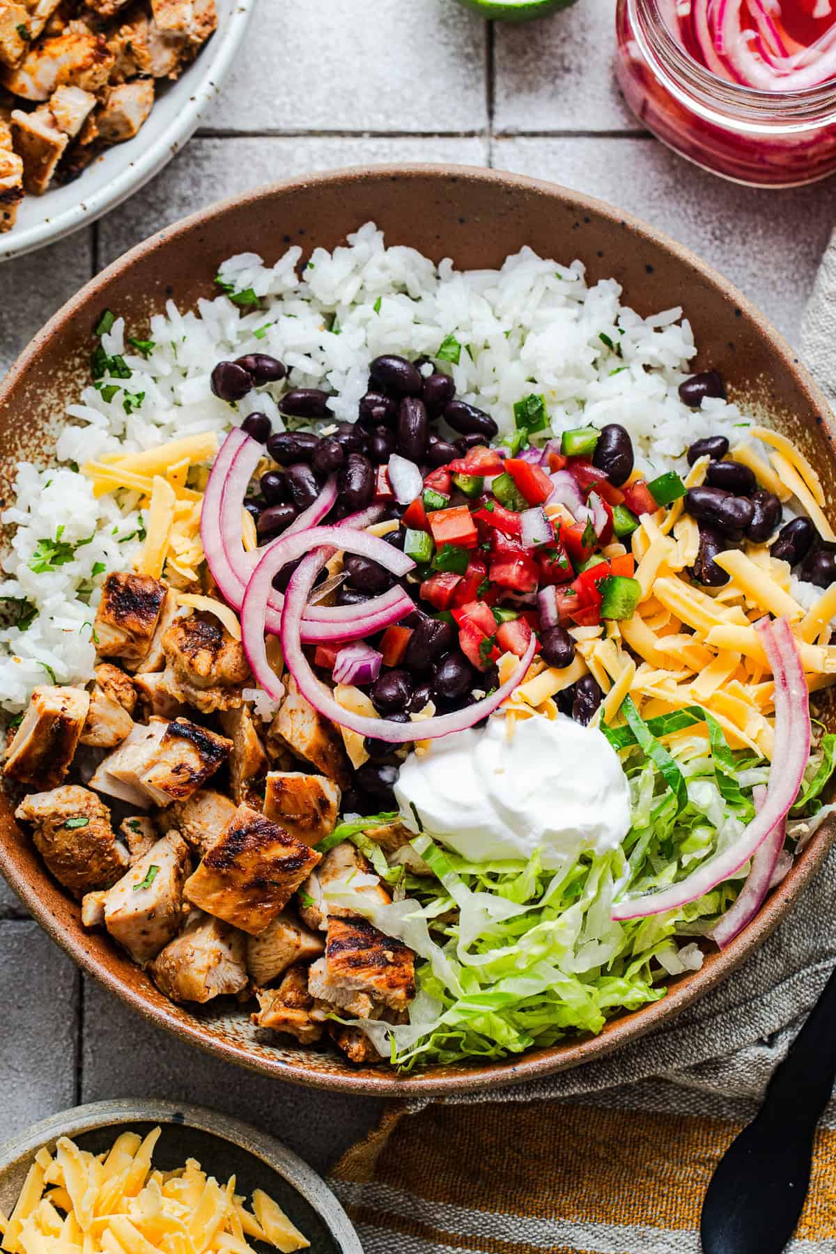 Copycat Chipotle chicken burrito bowl with cilantro lime rice, black beans, pico de gallo, and pickled red onions.
