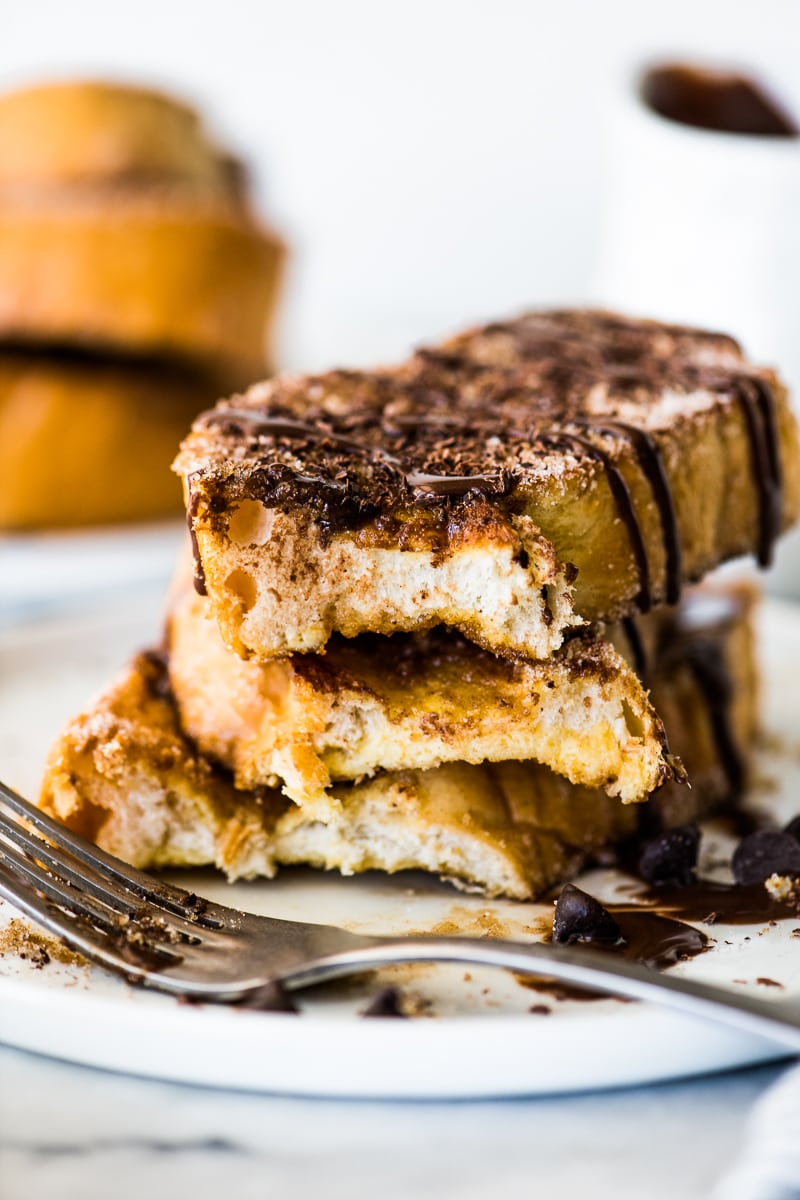 Cinnamon french toast on a white plate with a bite taken out.