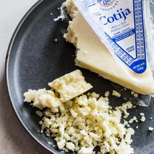 Crumbled cotija cheese on a gray stone plate.