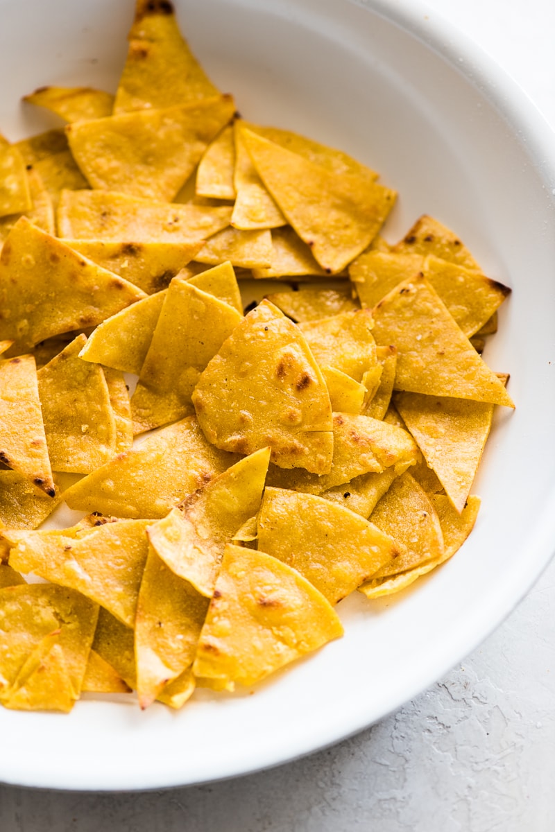 Fried corn tortillas for migas in a white skillet.