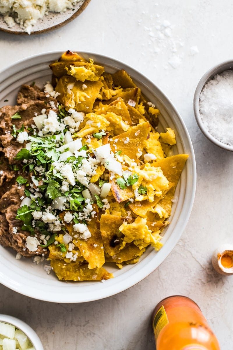 Migas made from crispy corn tortillas and scrambled eggs in a bowl with refried beans.