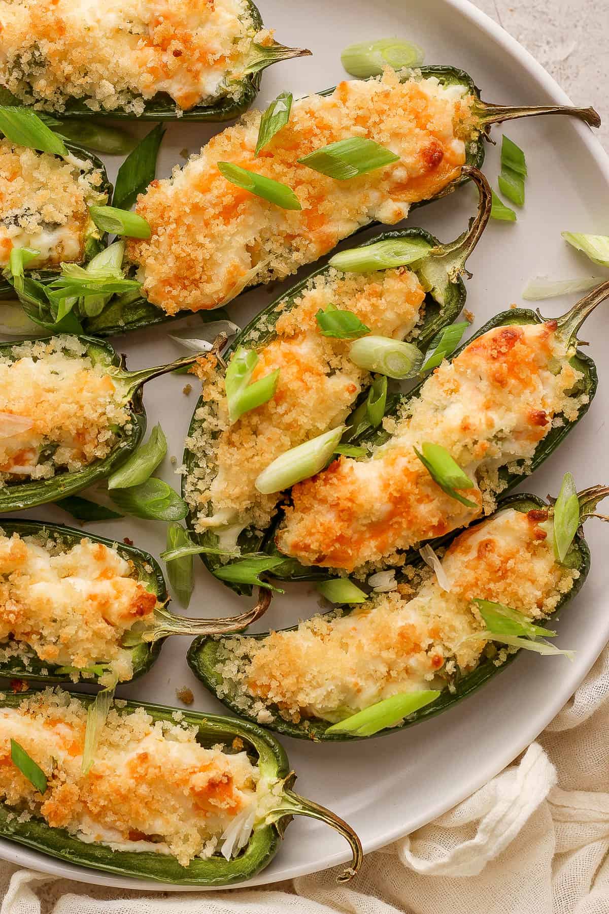 Jalapeño poppers on a plate garnished with sliced green onions.