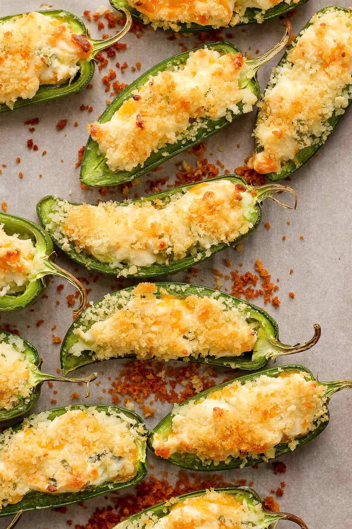 Crispy jalapeno peppers topped with panko breadcrumbs on a baking sheet.