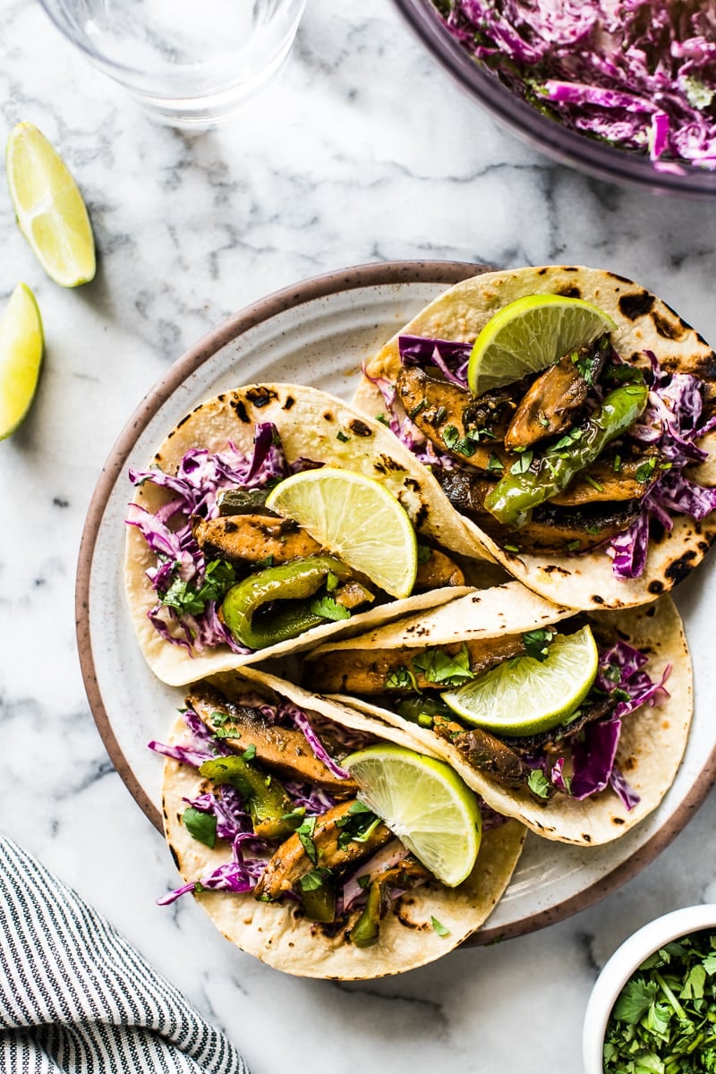 Overhead photo of vegetarian tacos filled with marinated portabello mushrooms, bell peppers and red cabbage slaw