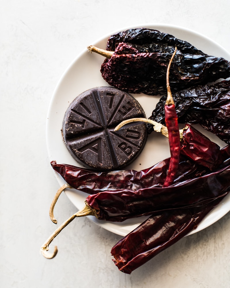 Dried guajillo, arbol and ancho chiles and Abuelita Mexican chocolate on a plate to make homemade enchilada sauce