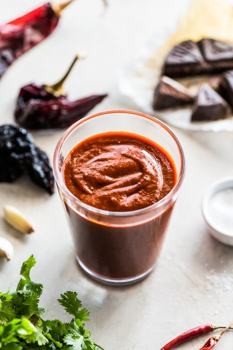 Authentic enchilada sauce in a jar surrounded by dried chiles.