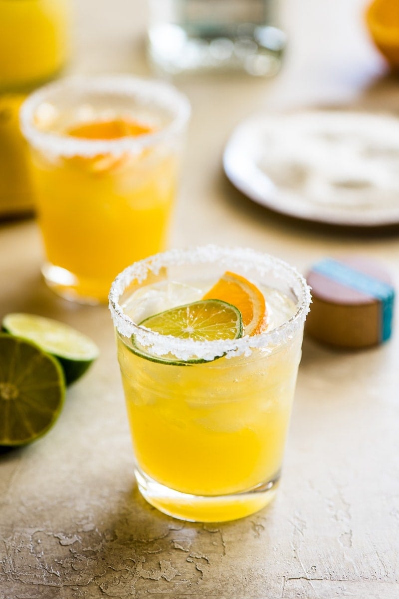 Skinny margarita cocktail glass garnished with sliced lime and orange.