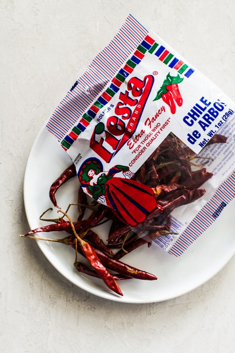 1 ounce bag of chile de arbol peppers on a white plate.