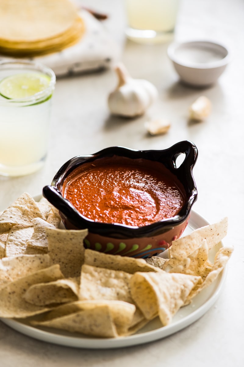 Chile de arbol salsa in an ornate Mexican-style brown bowl with tortilla chips around it.