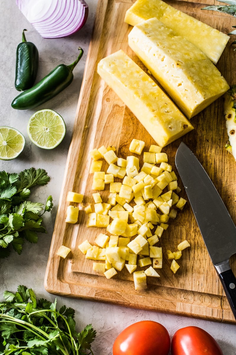 Diced pineapple on a light wooden cutting board.