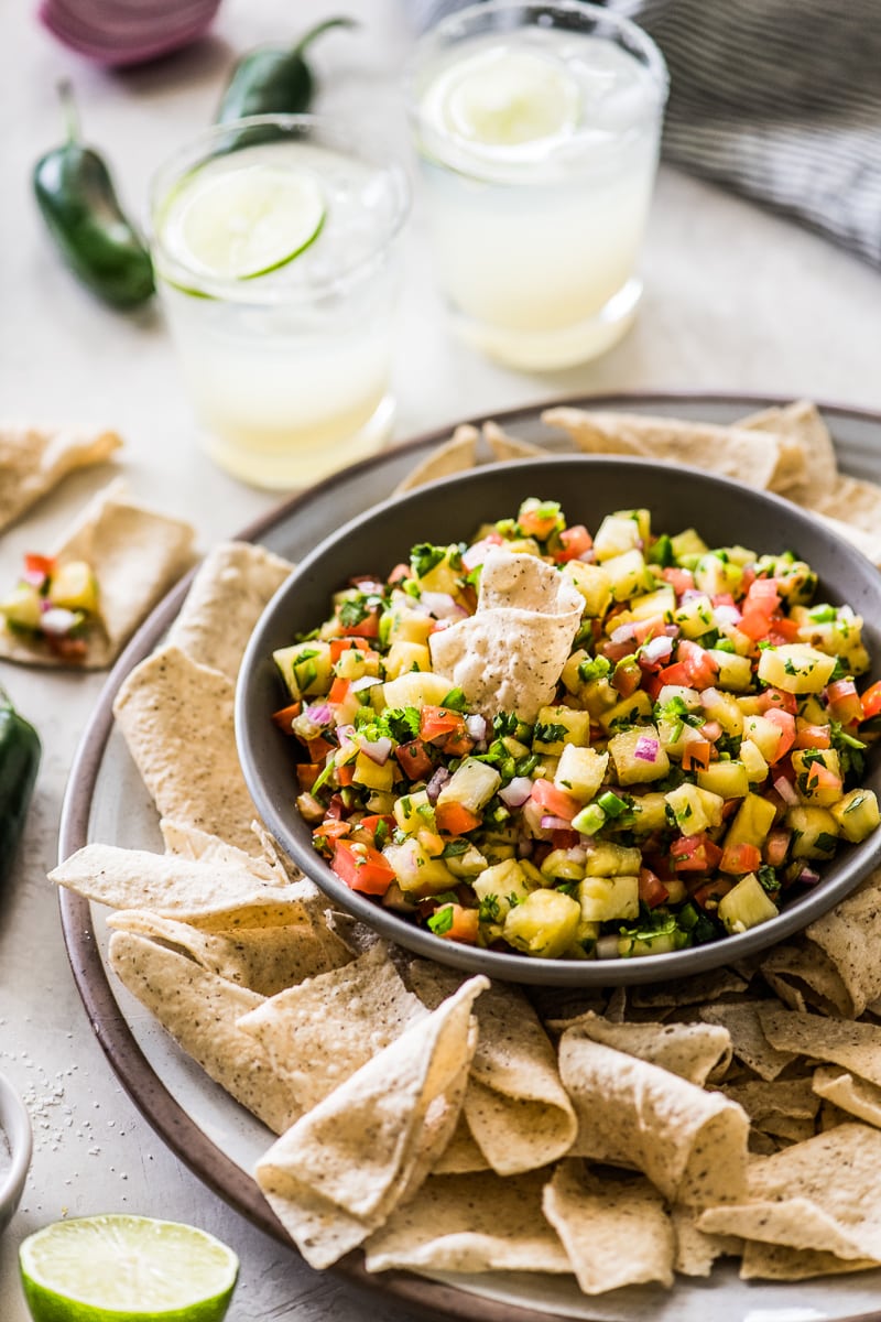 Pineapple salsa in a bowl with a tortilla chip scooping some out.