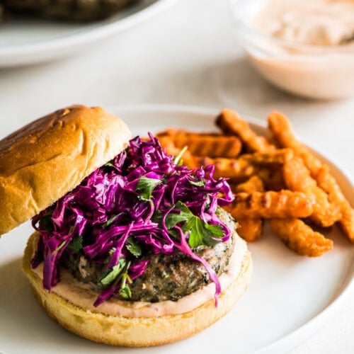 A grilled turkey burger sitting on a hamburger bun topped with chipotle lime mayo and a red cabbage slaw.