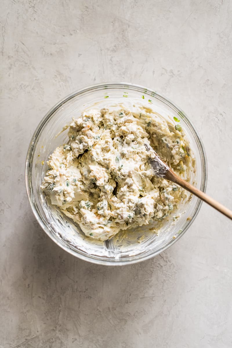 Jalapeno popper dip mixture in a glass bowl before being baked.