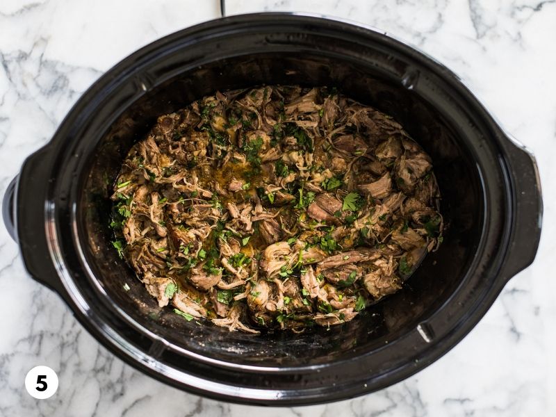 Juicy and flavorful carnitas in a slow cooker mixed with freshly chopped cilantro.