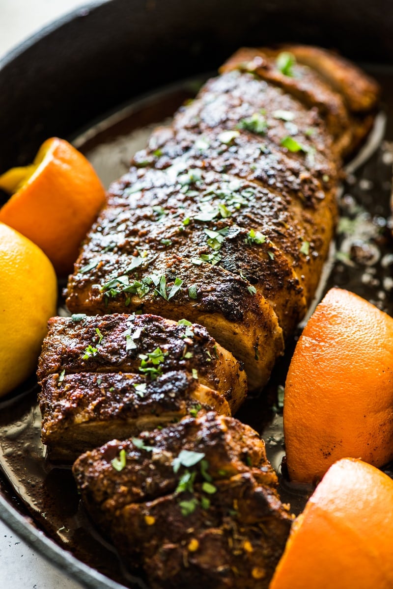 Gebratenes Schweinefilet in schwarzer gusseiserner Pfanne, garniert mit gehacktem Koriander.