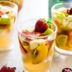 White sangria in a glass topped with summer fruit.