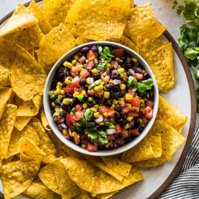 Black Bean and Corn Salsa in a white bowl surrounded by corn tortilla chips.