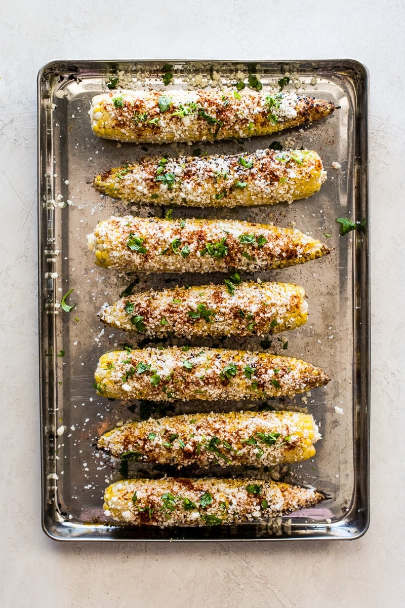 Mexican street corn (also known as elotes) on a large baking sheet.